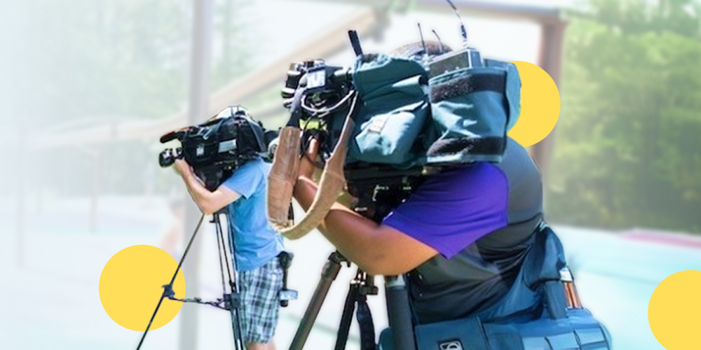 Two camera men recording in a park setting