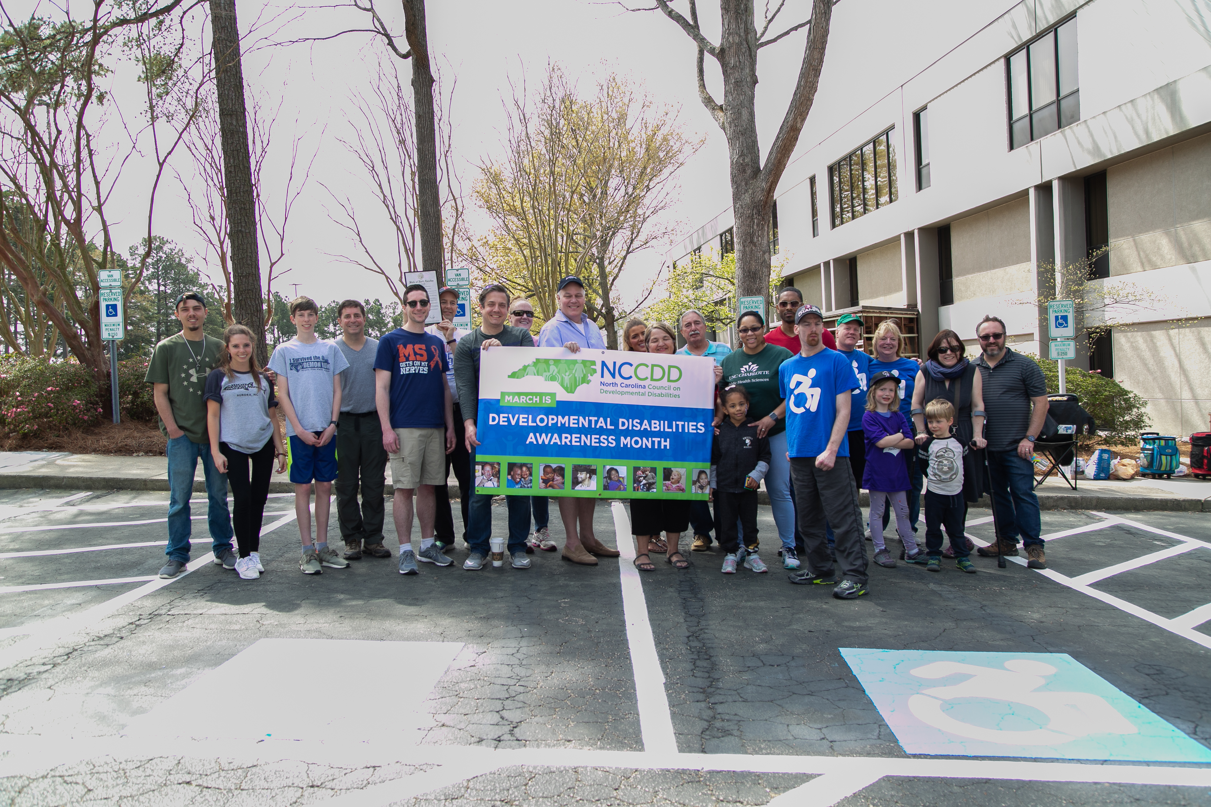 People celebrate DD Awareness Month at NCCDD offices. They are posing with a banner that says DD Awareness Month.